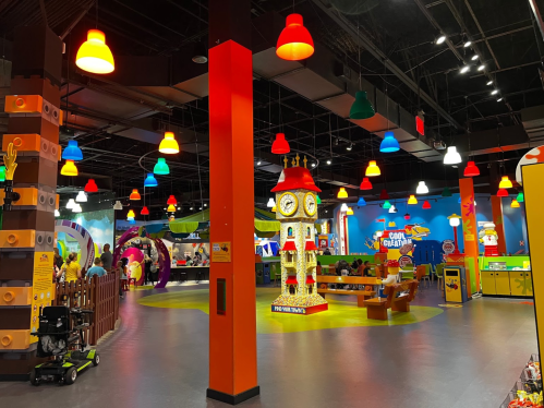 Colorful indoor play area with a clock tower centerpiece, bright lights, and various activity stations.