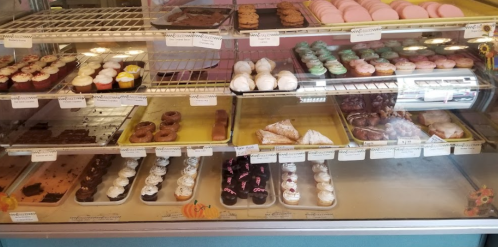 A display case filled with various baked goods, including cupcakes, cookies, donuts, and pastries.