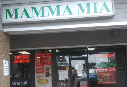 Sign for "Mamma Mia" restaurant with open pizza and espresso offerings, featuring bright neon lights and menu displays.