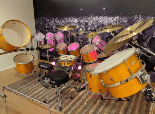 A vibrant drum set with yellow drums and cymbals, set against a backdrop of a cheering crowd.