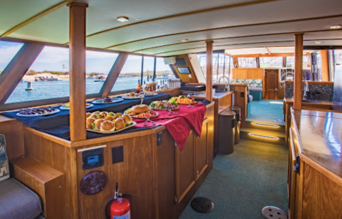 A beautifully arranged dining area on a boat, featuring a variety of dishes and a scenic view of the water outside.