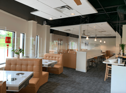 Modern restaurant interior with brown booths, glass dividers, and bright lighting, featuring a clean and spacious layout.