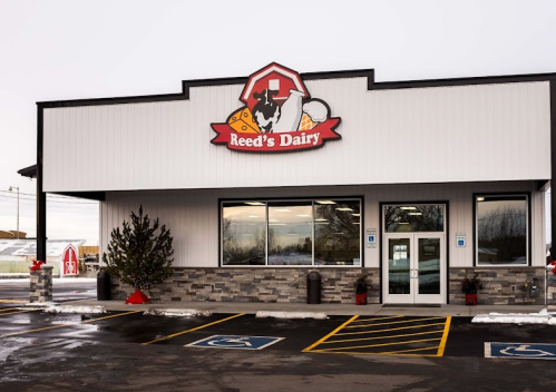 Exterior of Reed's Dairy store featuring a modern design, large windows, and a logo with a cow and dairy products.