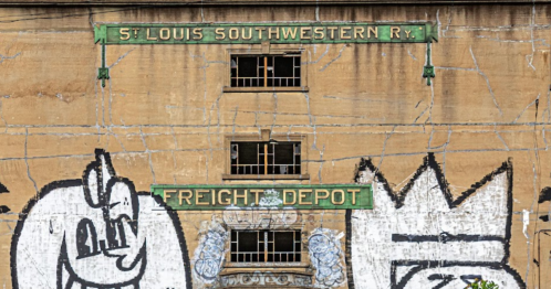 Graffiti-covered wall of the St. Louis Southwestern Railway Freight Depot, featuring large cartoonish designs.