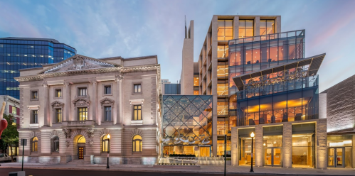 A modern building next to a historic structure, showcasing contrasting architectural styles in an urban setting.