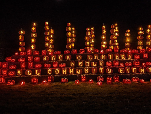 A vibrant display of illuminated jack-o'-lanterns arranged in a festive pattern for a community event at night.