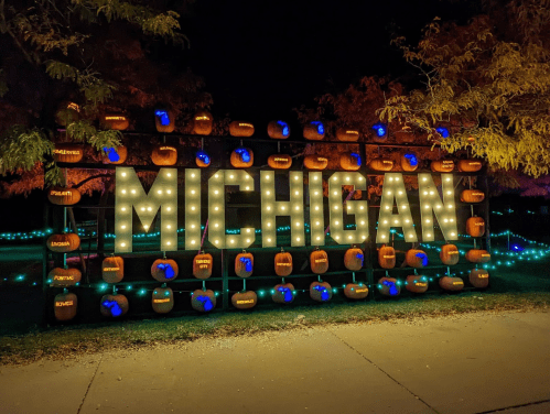 A decorative display spelling "MICHIGAN" with illuminated letters and pumpkins, set against a nighttime backdrop.