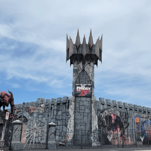 A spooky castle with a tall tower, featuring Halloween decorations and a sign for "Friday the 13th" event.