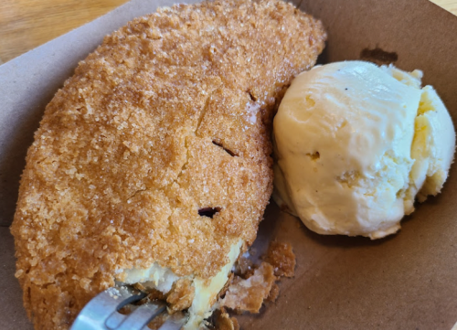 A golden-brown fried dessert with a crispy coating, served alongside a scoop of vanilla ice cream.