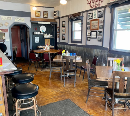 Cozy restaurant interior with wooden tables, chairs, and framed photos on the walls, featuring a warm, inviting atmosphere.