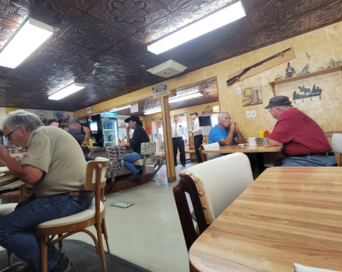 A cozy diner interior with patrons eating and chatting, featuring wooden decor and a vintage atmosphere.