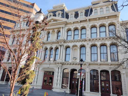 Historic building with ornate architecture, large windows, and a decorative facade, surrounded by modern structures.