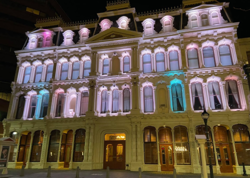 Historic building illuminated with colorful lights at night, showcasing its architectural details and grandeur.