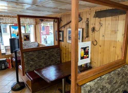 Cozy diner interior with wooden walls, booths, and decorative items, including a saw and a menu sign.