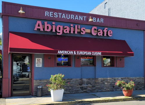 Exterior of Abigail's Cafe, featuring a red awning and signage for American and European cuisine. Flower pots in front.