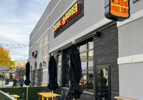 Exterior of a restaurant named "Chedda Burger," featuring outdoor seating and umbrellas.