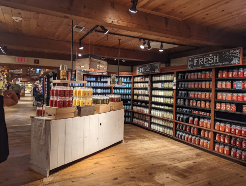 A cozy store interior with wooden shelves filled with colorful candles and jars, creating a warm atmosphere.