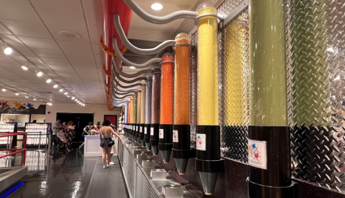 A colorful display of slushy machines in a bright, modern setting with people in the background.