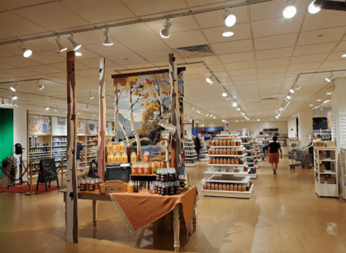A spacious store interior with shelves of products, a large mural, and customers browsing. Brightly lit and inviting atmosphere.