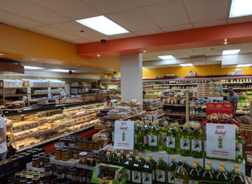 A bustling grocery store aisle filled with various food products, including jars, snacks, and baked goods.