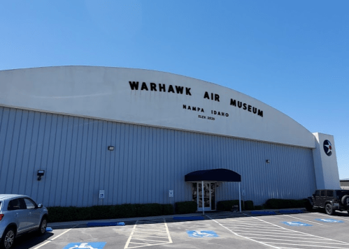 Exterior of the Warhawk Air Museum in Nampa, Idaho, featuring a large sign and clear blue sky.