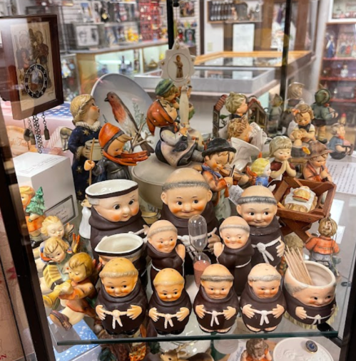 A display case filled with various vintage figurines, including monks and children, in a nostalgic collection.