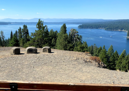 A scenic view of a lake surrounded by trees, with three stone structures in the foreground.