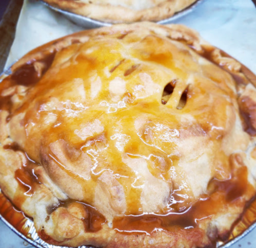 Golden-brown apple pie with a glossy glaze, resting in a silver pie tin.