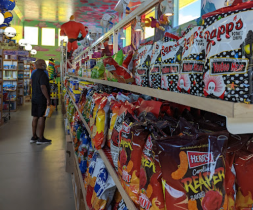 A colorful snack aisle filled with various chip bags, with a person browsing on the left.