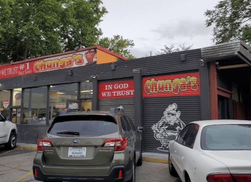 Exterior of Chunga's restaurant with a sign reading "In God We Trust" and a cartoon character on the wall.