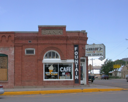 Historic brick building featuring a café and ice cream shop, with a vintage bank sign and a fountain display.