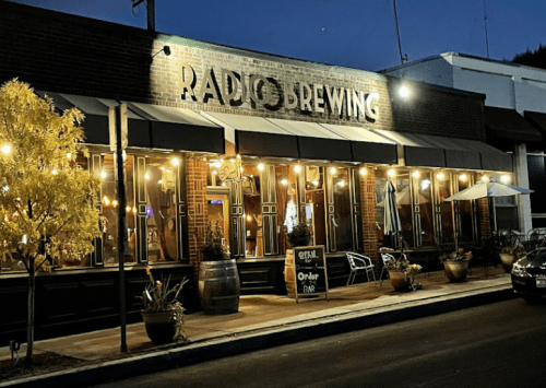 Exterior of Radio Brewing at night, featuring warm lights, outdoor seating, and a welcoming atmosphere.