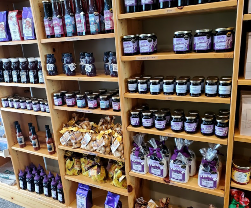 Shelves filled with various jars of jams, sauces, and snacks, all neatly arranged in a store.