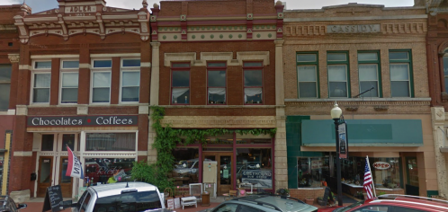 Historic buildings with shops, including a chocolate and coffee store, in a quaint downtown area.