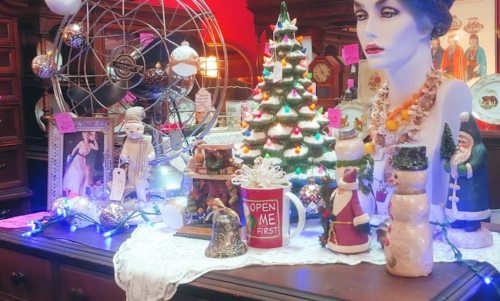 A festive display featuring a decorated Christmas tree, snowmen, and vintage ornaments on a wooden table.