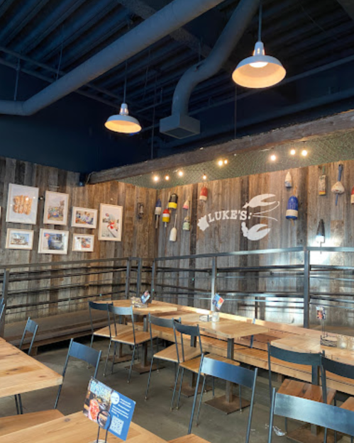 Interior of a restaurant with wooden walls, tables, and decorative fishing gear. "Luke's" logo displayed prominently.