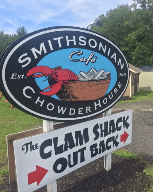 Sign for Smithsonian Café Chowder House, featuring a lobster and oysters, with a direction for "The Clam Shack Out Back."