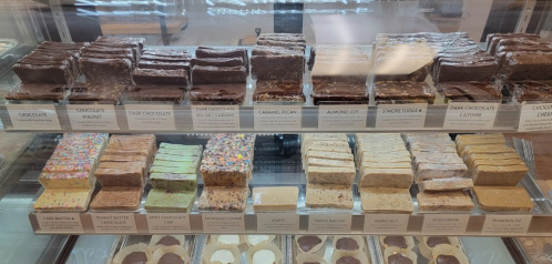 A display case filled with various fudge flavors, including chocolate, caramel, and seasonal varieties.