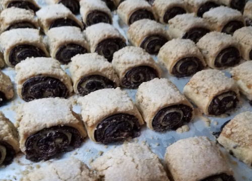 A close-up of rows of chocolate-filled pastry rolls topped with crumbly streusel.