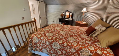 Cozy bedroom with a patterned bedspread, wooden furniture, and a warm, inviting atmosphere. Relaxing decor in the background.