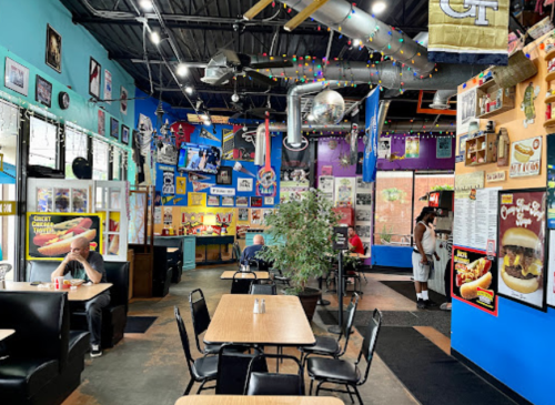 Colorful restaurant interior with tables, vibrant decor, and customers enjoying the lively atmosphere.