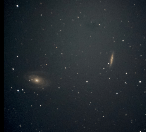 Two distant galaxies are visible against a dark starry background, showcasing their spiral shapes and faint light.