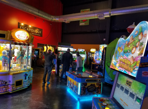 A vibrant arcade filled with various games and players enjoying their time in a lively atmosphere.