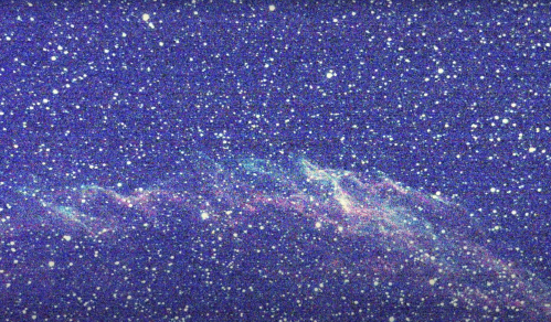 A starry night sky filled with countless stars and a colorful nebula against a deep blue background.
