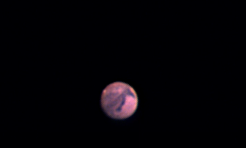 A close-up view of Mars, showcasing its reddish surface against a black background.
