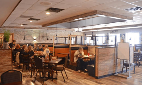 A cozy restaurant interior with booths and tables, featuring diners enjoying their meals in a warm atmosphere.