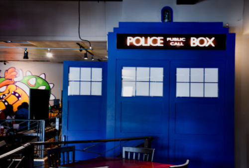 A blue police box replica with a "Police Public Call Box" sign, set in a colorful restaurant interior.