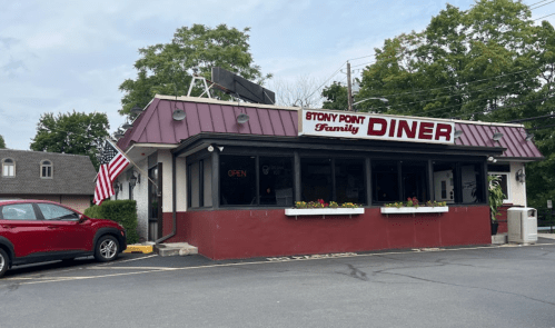 Exterior of Stony Point Family Diner, featuring a red car parked outside and an American flag. The diner is open.