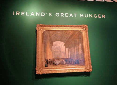 A framed painting displayed on a green wall, titled "Ireland's Great Hunger."