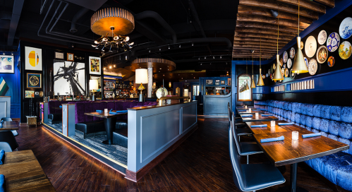 A stylish restaurant interior featuring plush seating, artistic decor, and a warm ambiance with dim lighting.